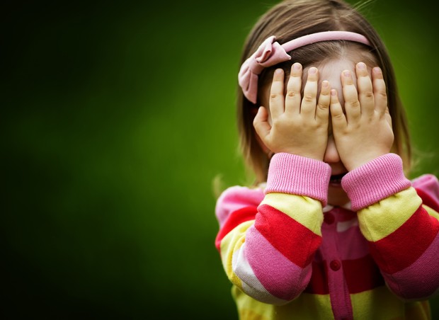 Criança escondendo o rosto com as mãos (Foto: Shutterstock)