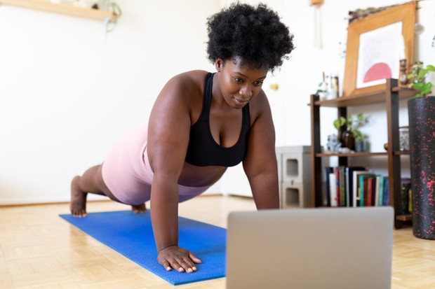 Strong woman doing workout at home in front of her laptop. Female in sportswear watching video tutorial online on her laptop and doing push ups. Woman doing online workout at home during covid-19 quarantine. (Foto: Getty Images)