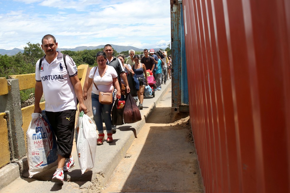Pessoas cruzam a ponte Simon BolÃ­var em meio a containers que ainda bloqueiam a passagem de automÃ³veis. â€” Foto: Carlos Eduardo Ramirez/Reuters