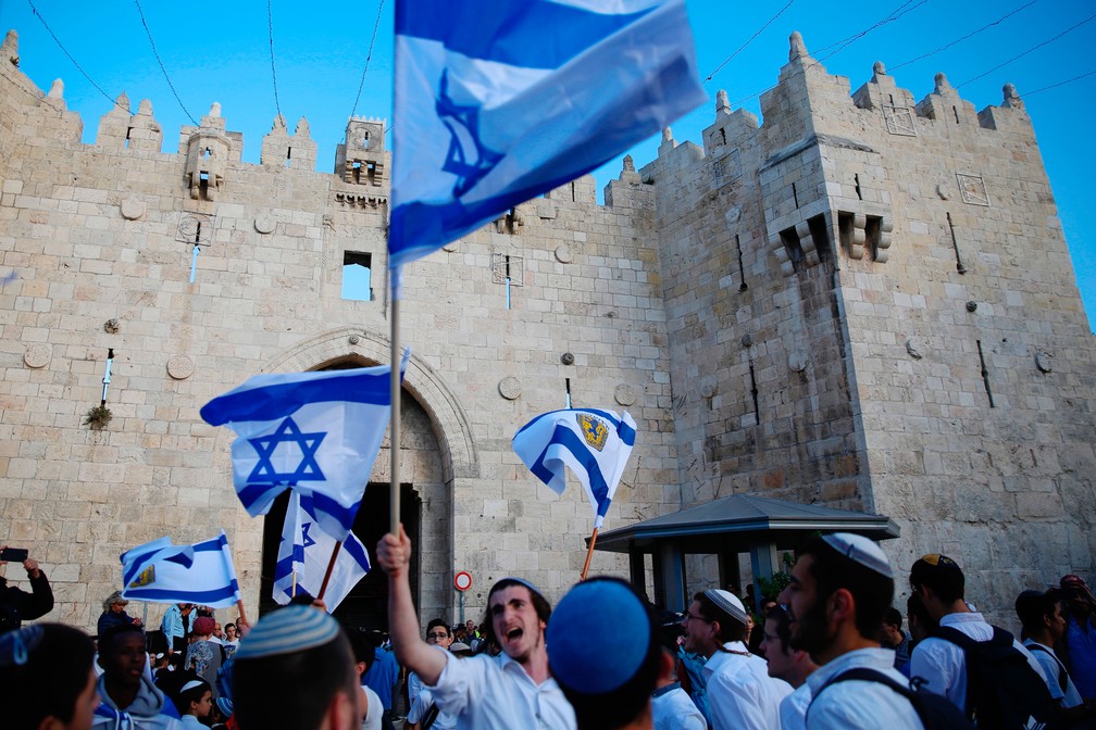Imagem de 13 de maio mostra israelenses com bandeiras na Porta de Damasco, uma das entradas de JerusalÃ©m antiga   (Foto: Ariel Schalit/ AP)