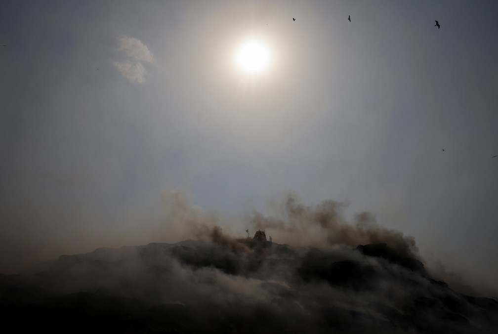 Uma escavadeira tenta conter o fogo criado pelo calor na capital indiana de Nova Delhi — Foto: Adnan Abidi/REUTERS
