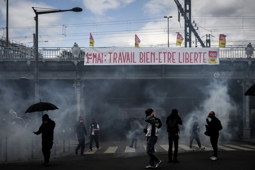 Manifestantes no meio de uma nuvem de gás lacrimogêneo durante um protesto deste 1º de maio em Lyon, terceira maior cidade da França. — Foto: JEFF PACHOUD / AFP