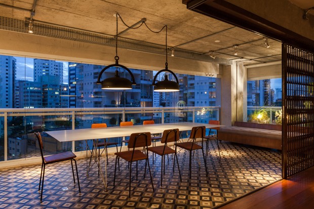 A sala de jantar ocupa o espaço da varanda com piso de ladrilho hidráulico e porta pantográfica (Foto:  Divulgação)