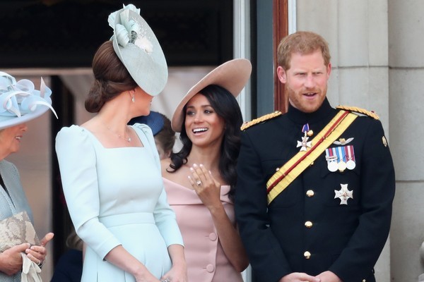 A atriz Meghan Markle com o Príncipe Harry enquanto observada por sua cunhada, Kate Middleton (Foto: Getty Images)