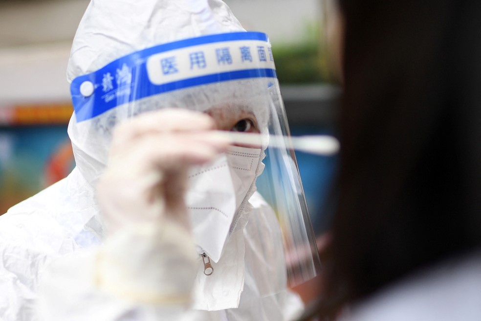 Profissional de saúde coleta amostra com cotonete de moradora de Wuhan, na China, para teste de Covid-19, nesta terça-feira (22). — Foto: STR / AFP