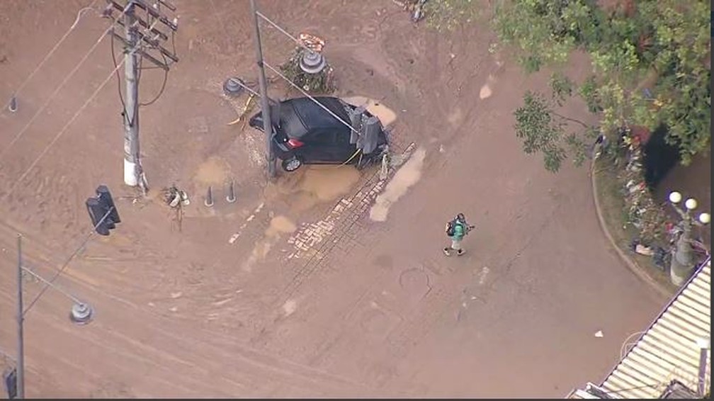 Carro suspenso pela força da água em Petrópolis — Foto: Reprodução/TV Globo