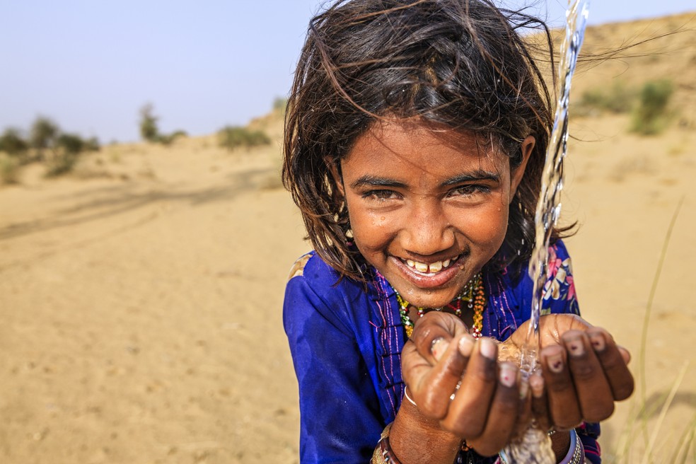 Menina indiana bebendo água doce em aldeia na desértica Rajasthan, Índia. — Foto: Hadynyah/GettyImages