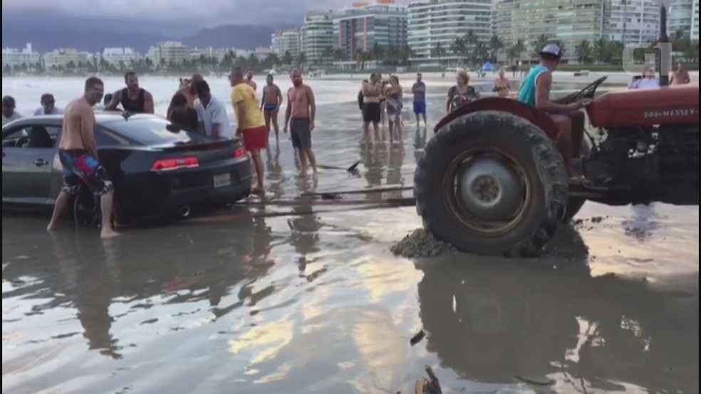 Banhistas tentam ajudar motorista que atolou na praia de Bertioga, SP. (Foto: Reprodução/Aconteceu em Bertioga)