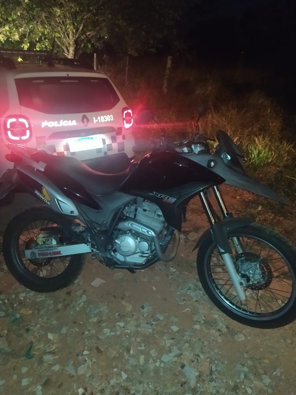 Motocicleta havia sido deixada embaixo de uma árvore, coberta por edredom e palhas secas — Foto: Polícia Militar