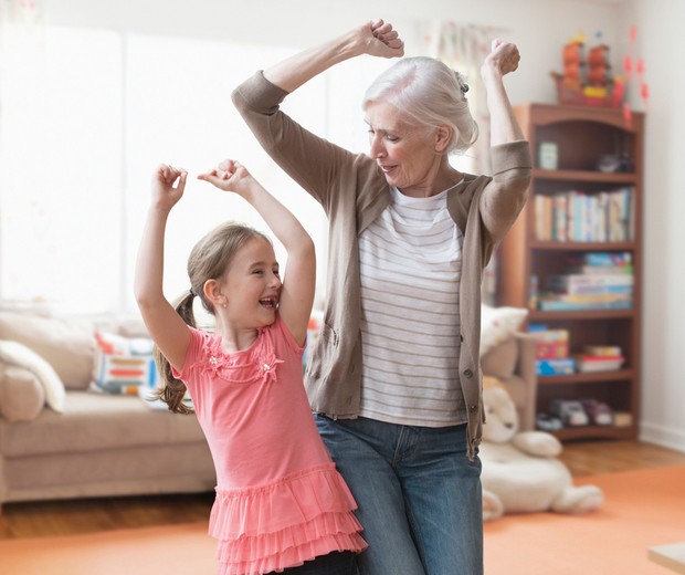 Caucasian grandmother and granddaughter dancing in living room (Foto: Getty Images)