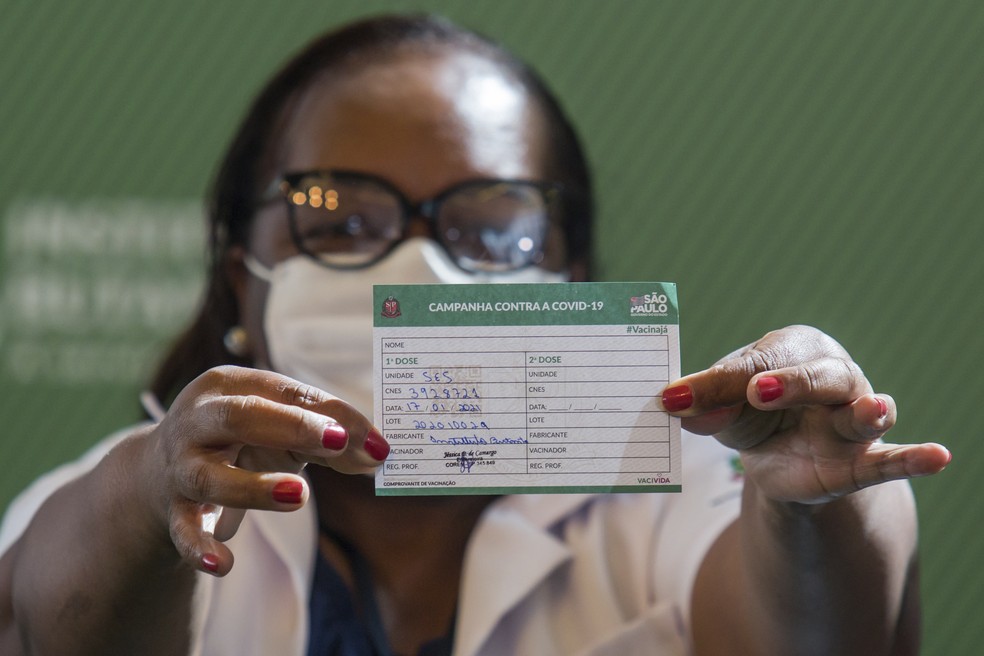 A enfermeira Mônica Calazans, de 54 anos, mostra seu cartão de vacinação após ser a primeira brasileira a receber a vacina CoronaVac no Hospital das Clínicas, em São Paulo, neste domingo (17)  — Foto: Carla Carniel/AP