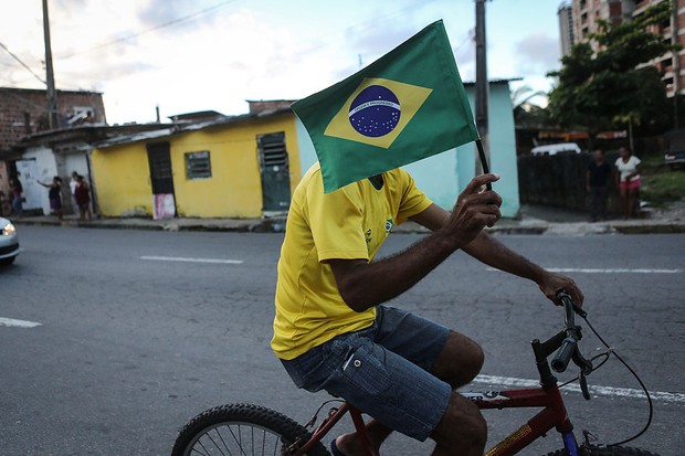Homem carrega uma bandeira do Brasil (Foto: Mario Tama/Getty Images)