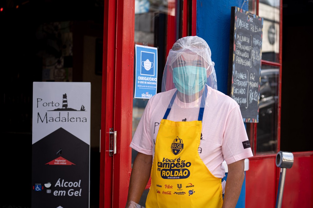 Funcionário de bar na Vila Madalena, em São Paulo, utiliza máscara e protetor facial durante a reabertura  — Foto: Marcelo Brandt/G1