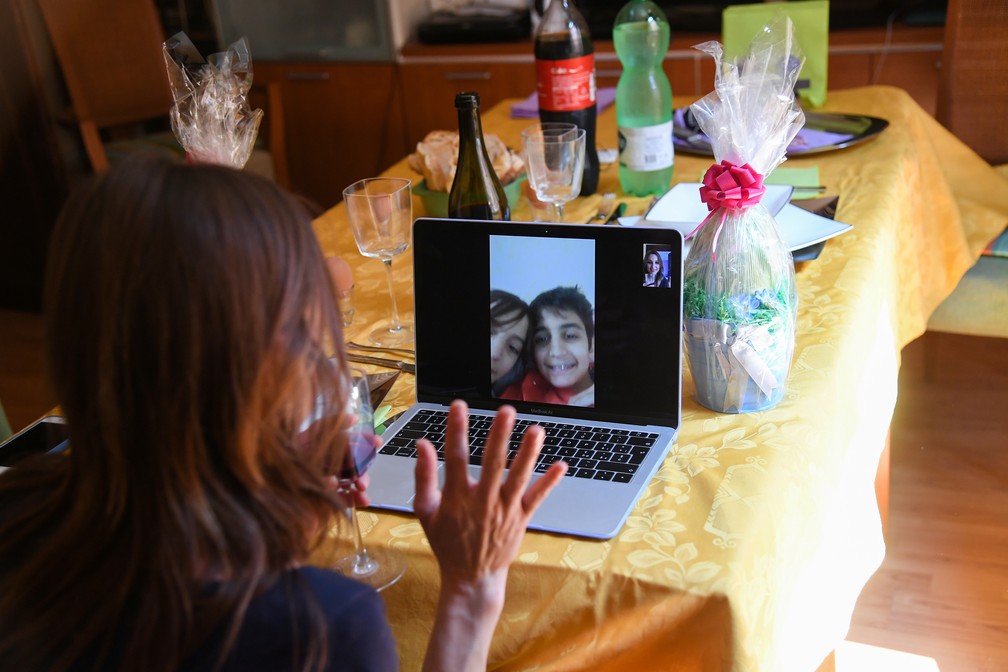 12 de abril - Uma mulher conversa com seus filhos em uma vídeo chamada durante um almoço de Páscoa em Roma, na Itália, devido ao isolamento social para conter casos de coronavírus — Foto: Alberto Lingria/Reuters