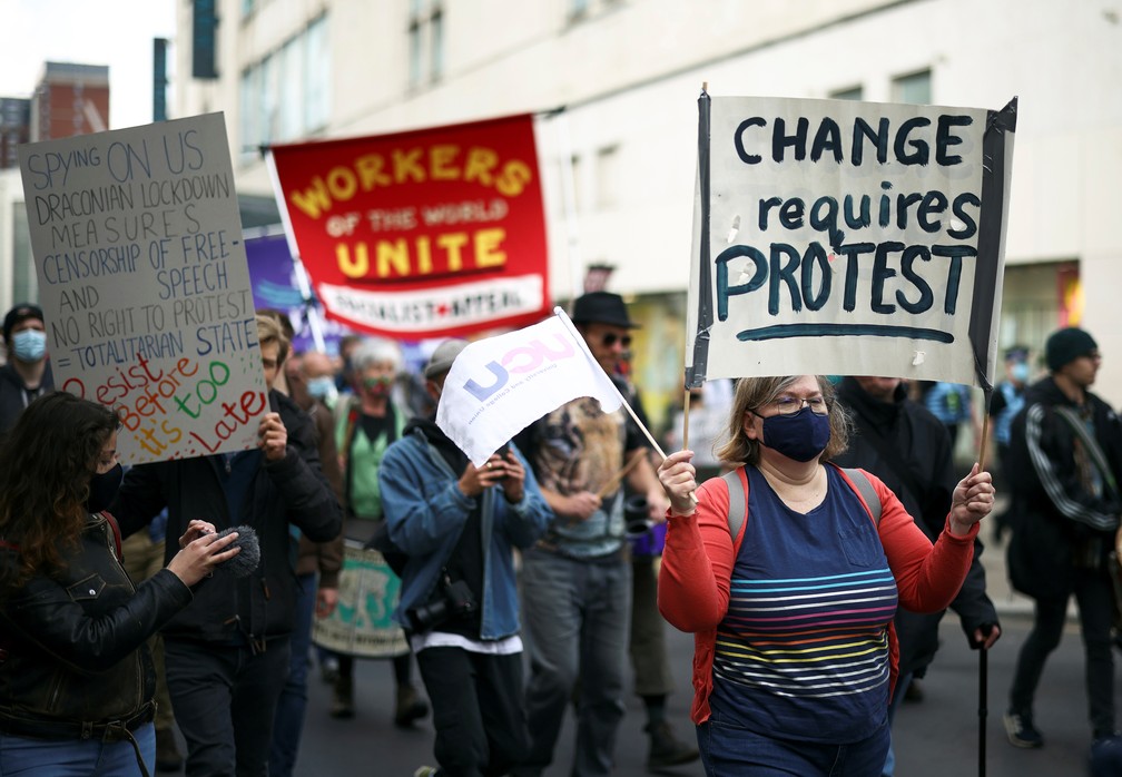 Manifestante segura um cartaz e uma bandeira durante protesto de 1º de maio em Bristol, na Inglaterra — Foto: Henry Nicholls/Reuters
