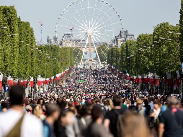 Pessoas caminham pela avenida Champs-Élysées, em Paris, fechada para o tráfego no domingo (8) (Foto: AP Photo/Kamil Zihnioglu)