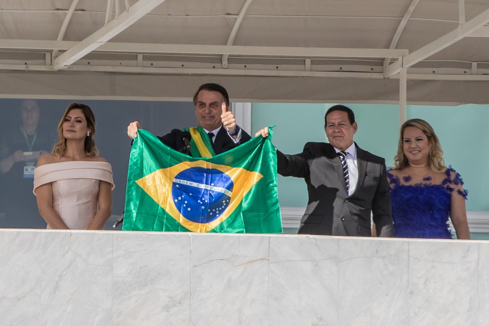 O presidente Jair Bolsonaro e o vice, Mourão, mostram uma bandeira do Brasil no Parlatório diante do público na Praça dos Três Poderes — Foto: Fábio Tito/G1