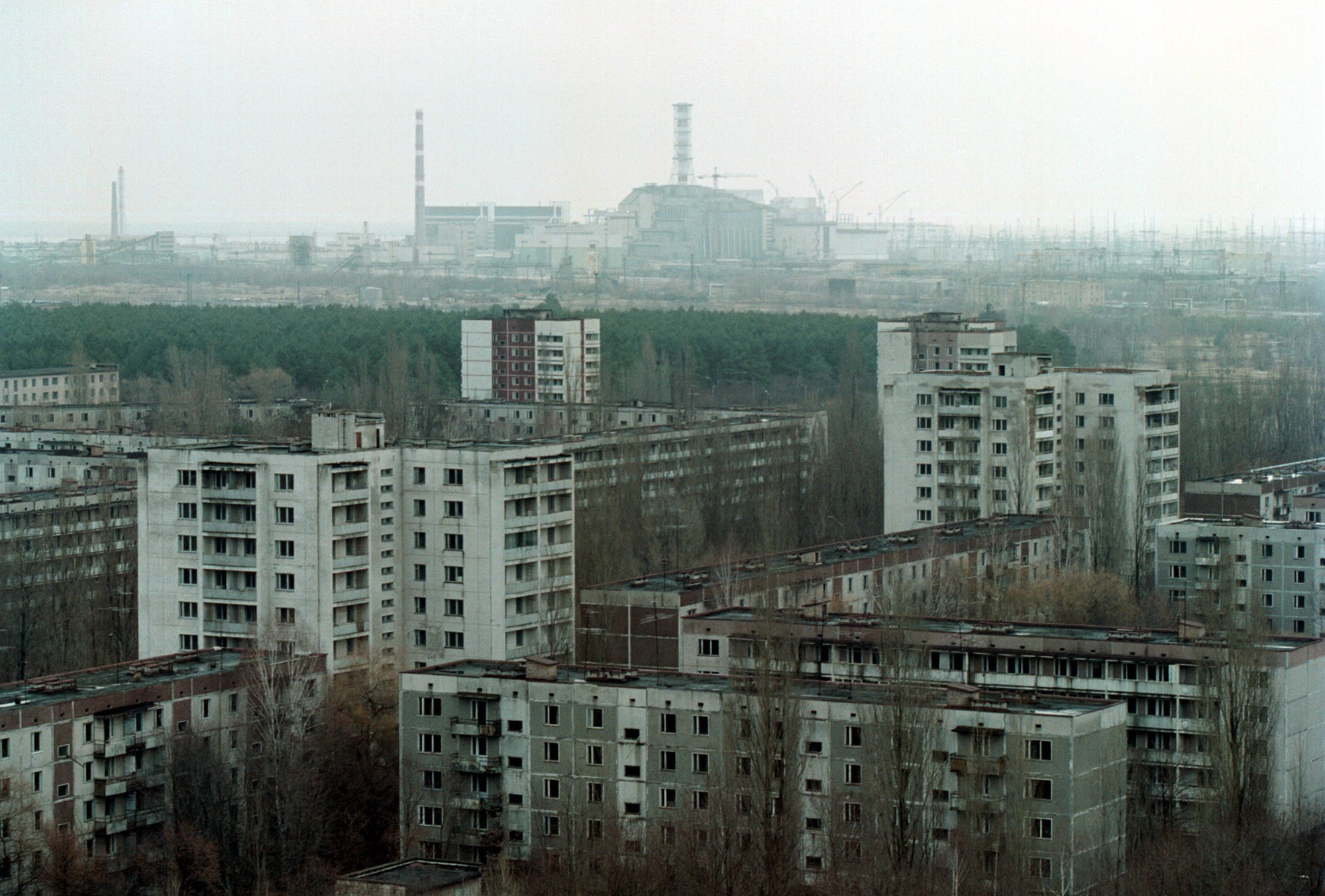 vista da cidade de pripyat com o quarto reator de chernobyl ao fundo - foto tirada em 2000 (Foto: getty)
