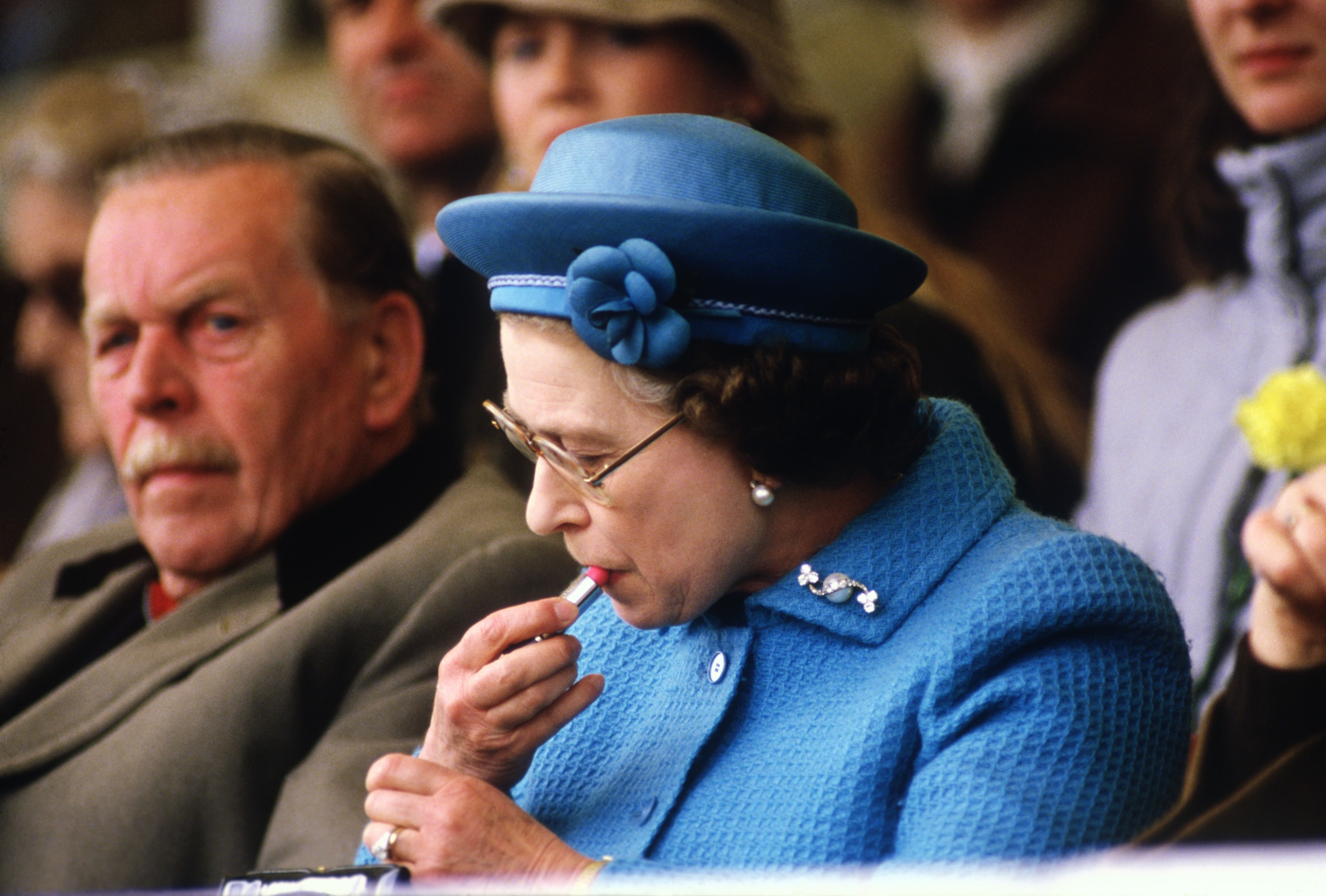 WINDSOR - MAY 11:   Queen Elizabeth II puts on lipstick in the Royal Box at the Windsor Horse Show on May 11, 1985. Prince Phillip was about to enter the dressage ring with his horse team.  (Photo by David Levenson/Getty Images) (Foto: Getty Images)