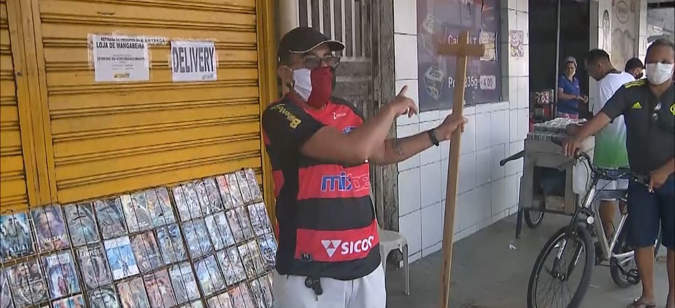 Pedagogo recorre a pedaço de madeira para manter distância em filas, em João Pessoa — Foto: TV Cabo Branco/Reprodução