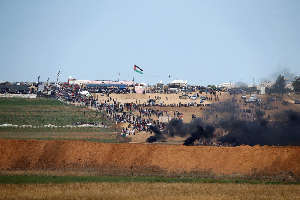 Fumaça é vista durante confronto entre palestinos e soldados israelenses nesta segunda-feira (14) na fronteira da Faixa de Gaza com Israel (Foto: Baz Ratner/Reuters)