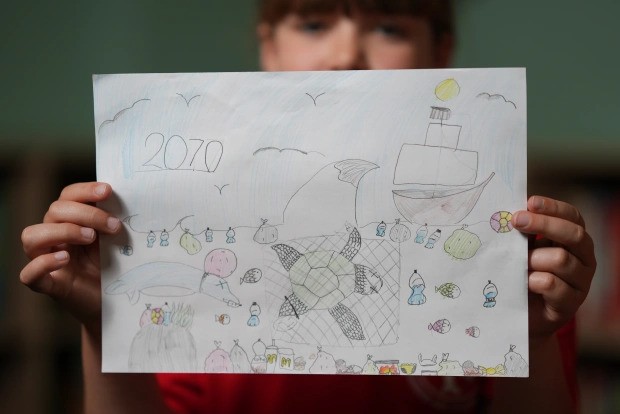 Criança mostra desenho sobre oceano (Foto: Reprodução/The Sun)