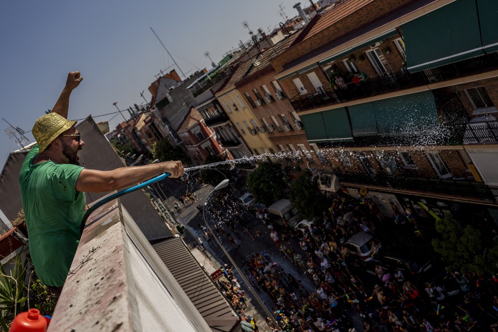 Um homem joga água de uma mangueira durante a 'Batalha Naval de Vallecas', um popular festival anual nas proximidades de Madri (Espanha). — Foto: AP Photo/Manu Fernandez