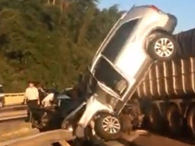 Carro ficou pendurado em carreta na rodovia (Foto: Reprodução / TV TEM)