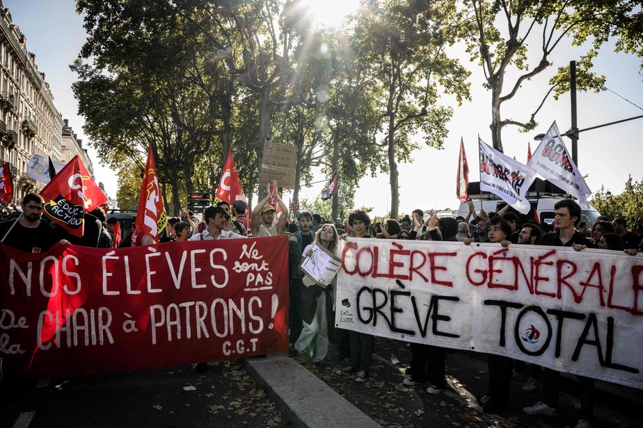 Manifestantes carregam placa com os dizeres 'Raiva geral, greve total' (direita) durante protesto em Lyon, na França