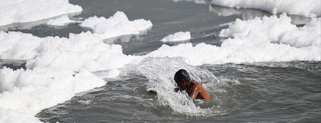 Homem se banha no poluído rio Yamuna, em Nova Délhi — Foto: Money SHARMA / AFP