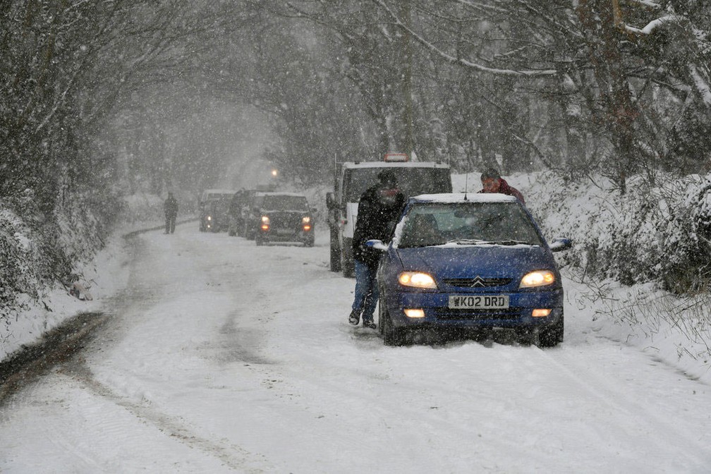 Pessoas empurram carro em estada no sul da Inglaterra nesta quarta-feira (28)  (Foto: Ben Birchall/PA via AP)