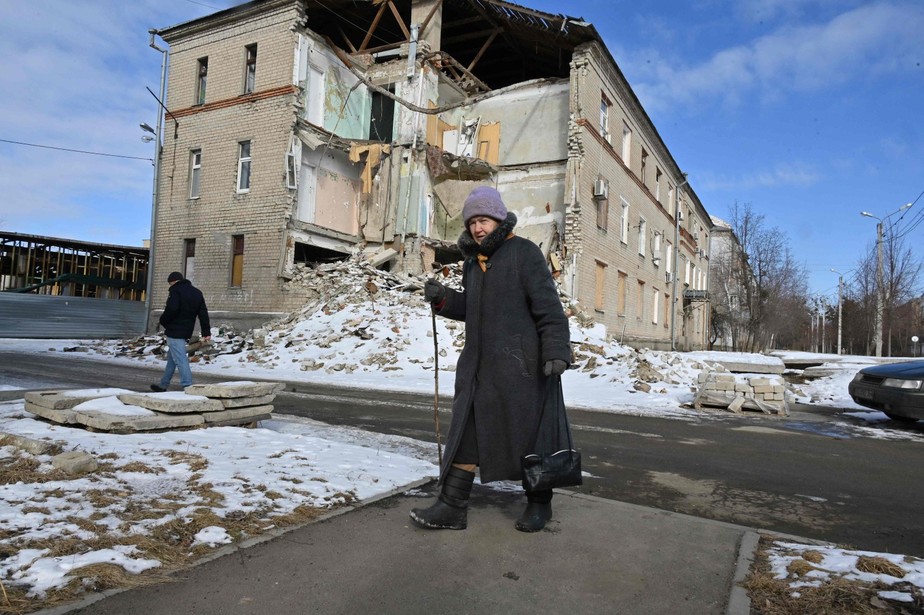Moradores caminham em meio ao cenário de destruição em Kharkiv, na Ucrânia