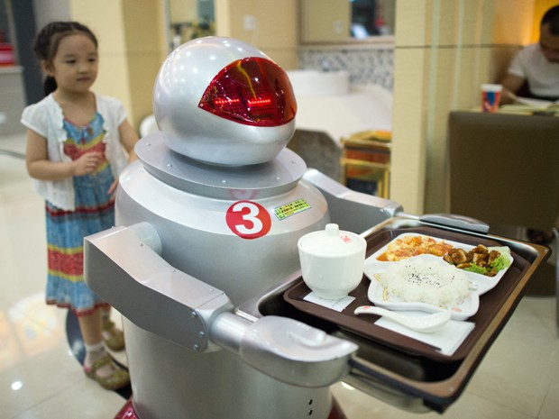 Dois robôs dão as boas-vindas à clientela e quatro pequenos androides levam às mesas seus pratos suculentos (Foto: AFP)