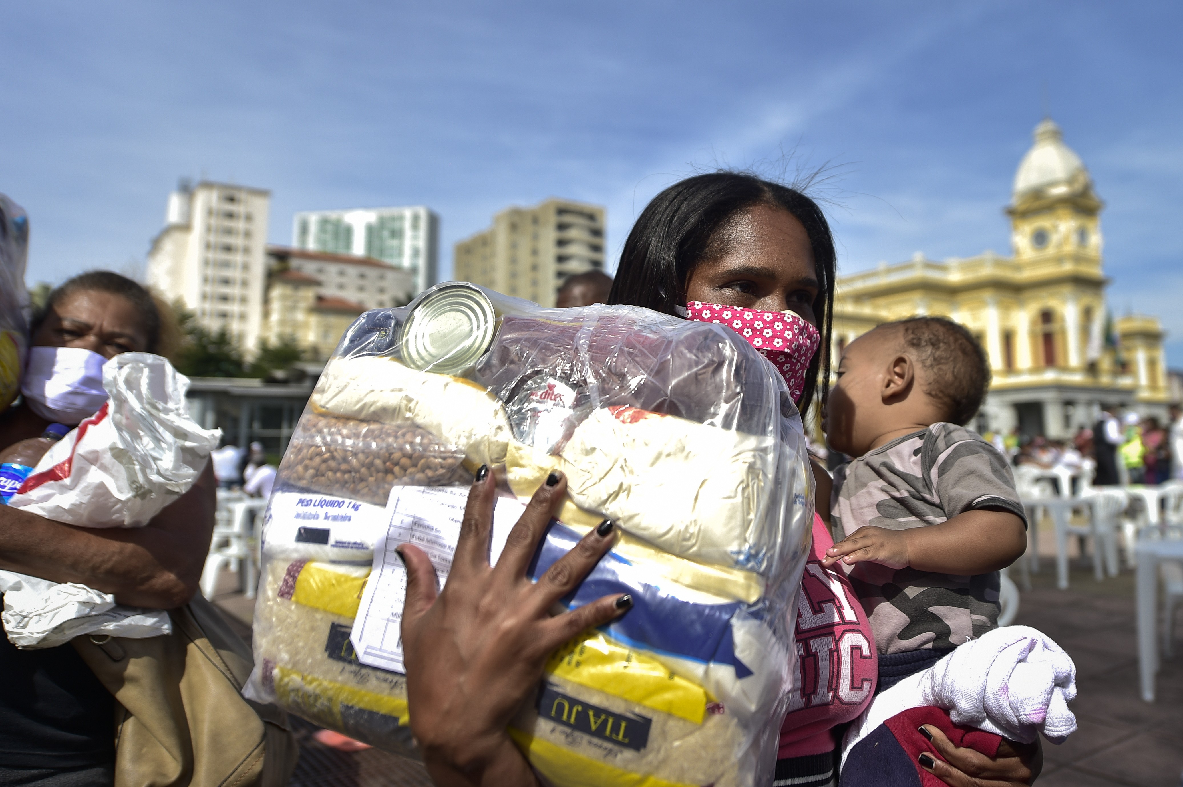 Uma mulher e uma criança estão na fila para pegar comida, frutas e água na Praça da Estação em 5 de junho de 2020 em Belo Horizonte (Foto:  Pedro Vilela / Getty Images)