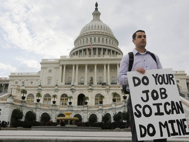 Funcionário mostra cartaz em frente ao Capitólio, em Washington: 'Faça o seu trabalho para que eu possa fazer o meu' (Foto: Larry Downing/Reuters)