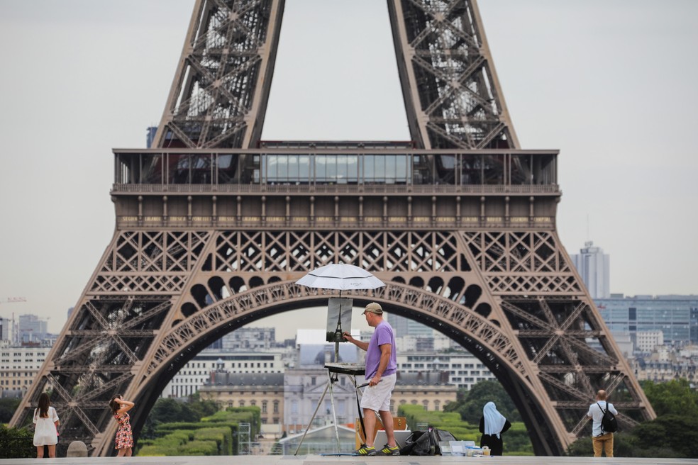 Um artista pinta a torre Eiffel na praça Trocadero, em Paris (Foto: Ludovic Marin/AFP)