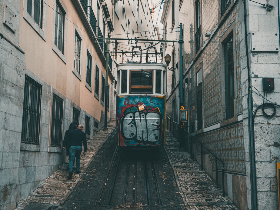 Pedestres caminham ao lado do bonde em Lisboa