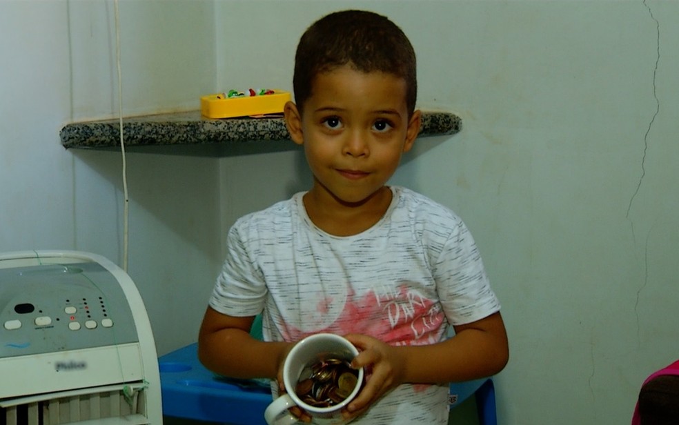 Guilherme Gomes, de 4 anos, mostra os R$ 18 em moedas que dará a quem achar Faísca — Foto: Reprodução/TV Anhanguera