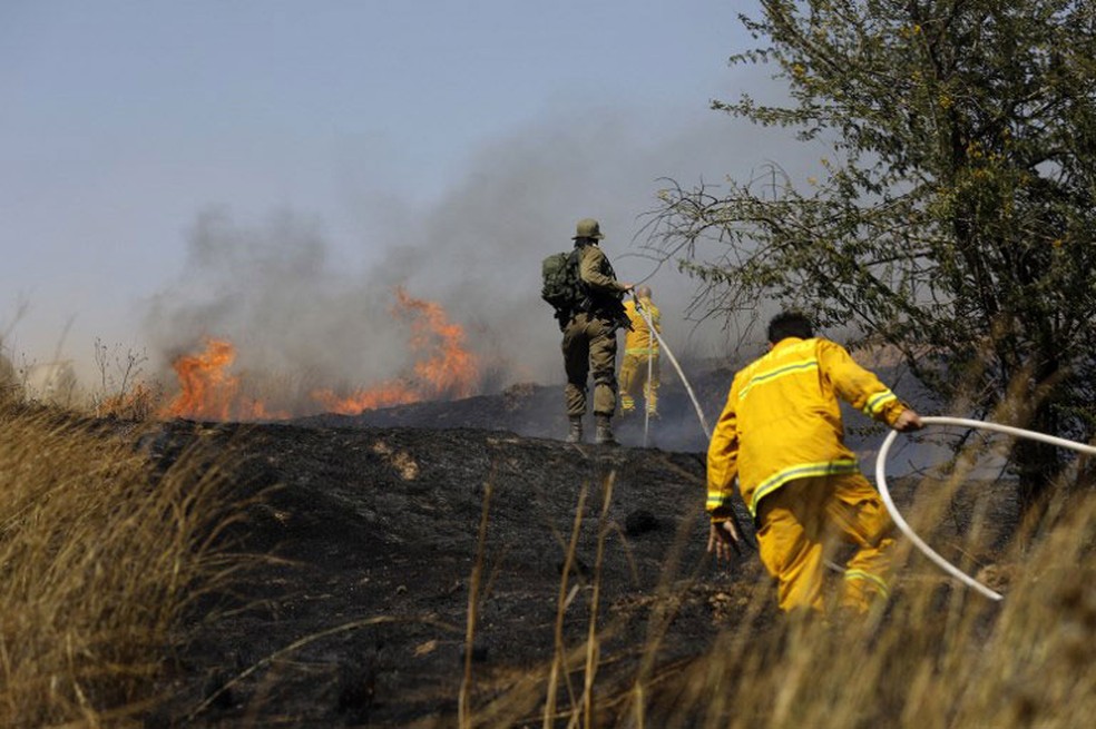 Bombeiros israelenses trabalham para extinguir fogo em campo prÃ³ximo ao Kibbutz de Kissufim, perto da fronteira com Gaza  (Foto: Menahem Kahana / AFP)