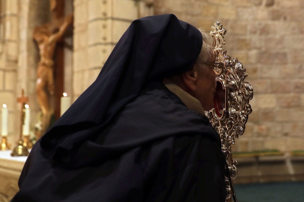 Freira cristã beija relíquia de madeira que se acredita pertencer à manjedoura de Jesus na igreja de Notre Dame em Jerusalém, nesta sexta-feira (29) — Foto:  Mahmoud Illean/AP