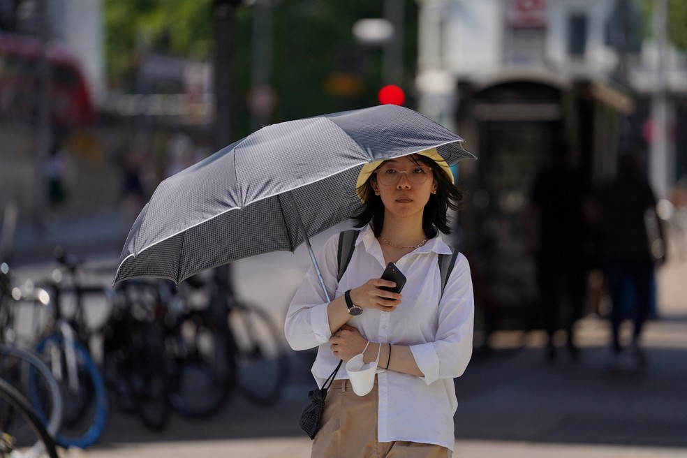 Mulher se protege com guarda-chuva durante onda de calor em Londres, nesta segunda-feira (18) — Foto: Maja Smiejkowska/Reuters