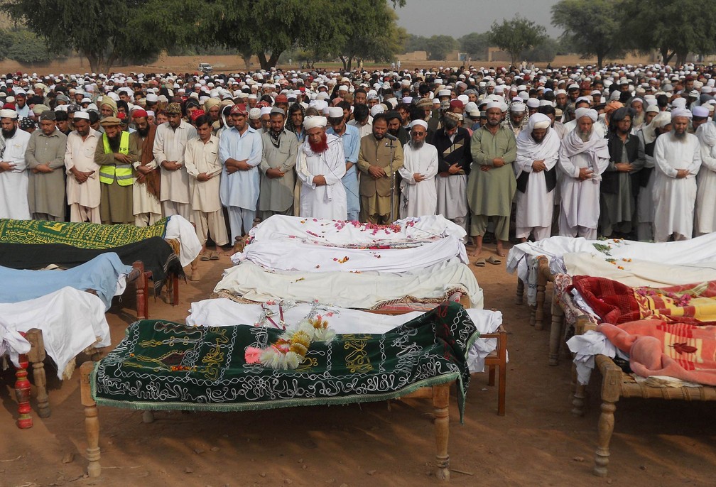 Familiares e conhecidos participam do funeral das vítimas de um acidente de ônibus ocorrido durante a noite que deixou no mínimo 26 mortos em Kohat, na província de Khyber Pakhtunkhwa, no Paquistão (Foto: Basit Shah/AFP)