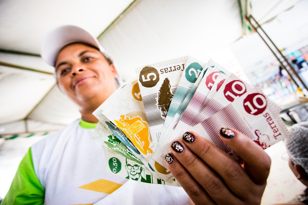A agricultora e feirante Elisangela Bezerra mostra as moedas Terra (Foto: Jonathan Lins / G1)