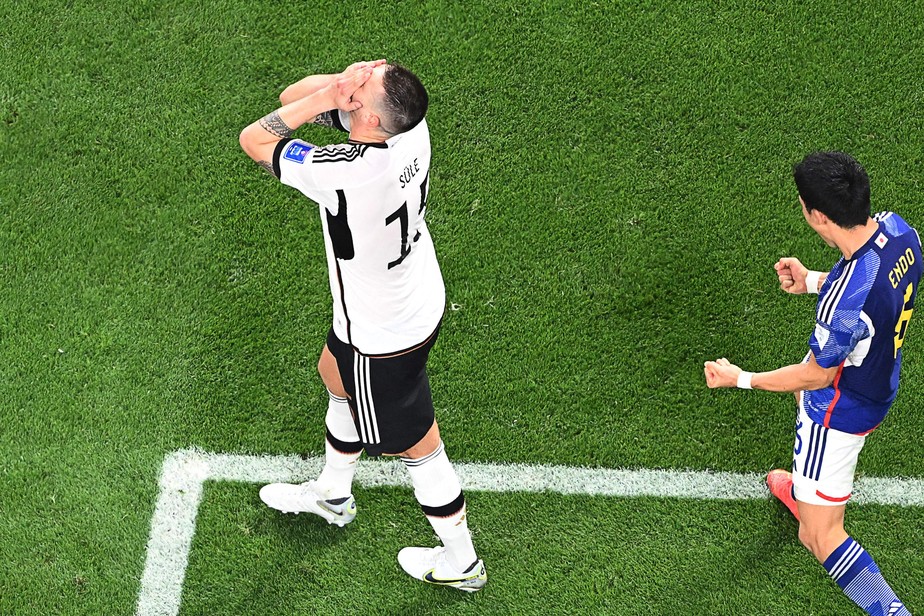 Zagueiro Suele, da Alemanha, lamenta enquanto japonês Endo comemora vitória de sua seleção na Copa do Mundo