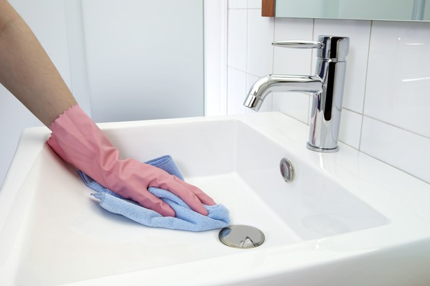 The woman, who is cleaning the washbasin with microfiber cloth and gloves (Foto: Getty Images)