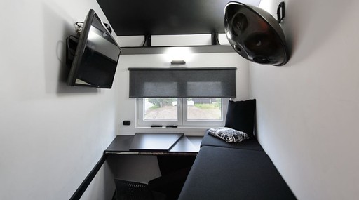 No andar de cima, o compacto quarto inclui cama, escrivaninha, cadeira e televisão