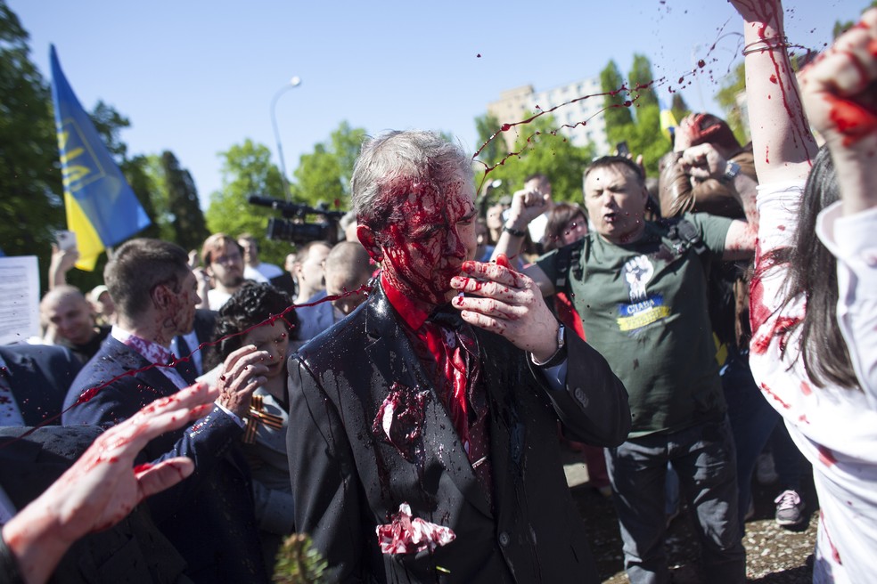 Embaixador da Rússia em Varsóvia, na Polônia, deixa ato após ser atingido por tinta vermelha lançada por manifestantes — Foto: Maciek Luczniewski/ Associated Press