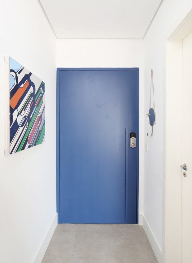 Hall de entrada | Porta pintada de azul. Quadro dado de presente de casamento pela irmã do morador, que trabalha em uma galeria em Londres, da artista Sarah Morris  (Foto: Mariana Ortis/Divulgação)