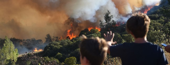 Crianças observam incêndio florestal perto de Gignac, sul da França, resultado da onda de calor que assola a Europa  — Foto: SYLVAIN THOMAS / AFP