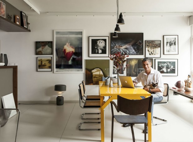 O morador Eder Chiodetto em sua sala de jantar, com mesa amarela da Micasa, cadeiras Cesca, quadros de fotografias pendurados na parede (Foto:  Foto: Edu Castello / Editora Globo)